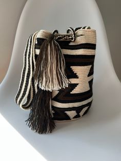 a black and white bag with tassels on the handle sitting on a chair