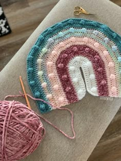 a crocheted pot holder with yarn next to it and a ball of thread