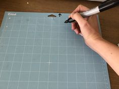 a person using a pen to write on a piece of blue paper next to a ruler