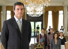 a man in a suit and tie standing in front of a room full of people