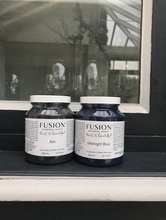 two bottles of black liquid sitting on top of a window sill