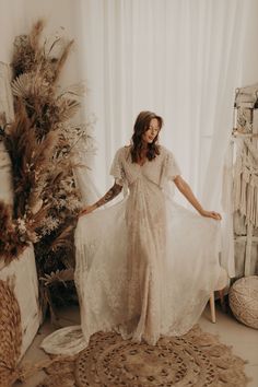 a woman in a white dress standing next to a christmas tree with feathers on it