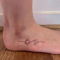 a person's foot with a small sun and arrow tattoo on the bottom of it