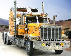 a large yellow truck is parked on the side of the road in front of some hills