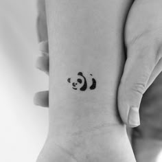 a small panda bear tattoo on the wrist