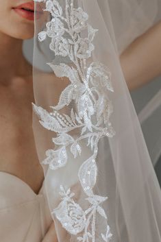 a woman wearing a veil with flowers and leaves on the side is looking down at her shoulder