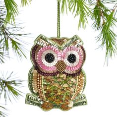 an owl ornament hanging from a pine tree with lots of sequins