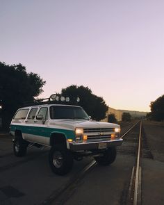 a white and green truck parked on train tracks