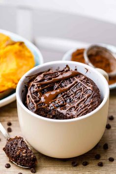 a bowl filled with chocolate pudding next to other desserts on a wooden table top