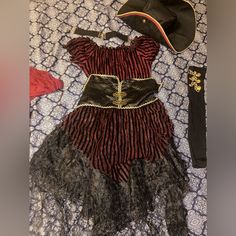 a pirate costume laying on top of a bed next to a hat and other items