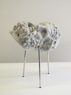 two white sculptures sitting on top of metal legs