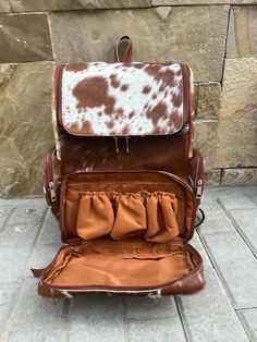 This large personalized cowhide diaper bag  backpack is perfect for those who need to be on the go while staying stylish. With enough space to fit a laptop, diaper bag essentials, and other items, this is the perfect functional accessory for your daily commute.   Real cowhide   Genuine leather back with padded back handles  Personalization : Optional . personalization will be done with contrast leather tag    Outer large pockets  Bottle or feeder pocket on front  Inner pockets Padded comfortable leather shoulder straps  fastening zippers Spacious and durable  Can accommodate laptop , files folders, toiletries, daily essentials, mobile, charger and many more Ideal for daily backpack, laptop bag backpack, diaper bag, travel backpack, school backpack  etc  Dimensions: 12″L X 14″H X 6″W Each c Groomsmen Gift Bags, Diaper Bag Essentials, Large Backpack Travel, Laptop Travel Bag, Laptop Travel, Cowhide Bag, Mommy Bag, Tan Bag, Multipurpose Bag