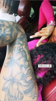 a woman laying on top of a red leather couch next to a man with tattoos