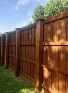 a wooden fence with grass and trees in the background