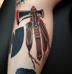 an arm with some tattoos on it that has arrows and feathers attached to the cross