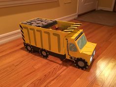 a yellow toy truck sitting on top of a hard wood floor next to a door