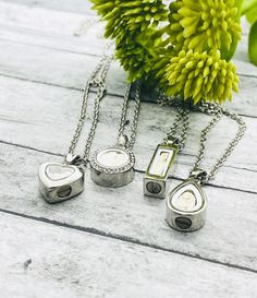 three pieces of jewelry sitting on top of a wooden table next to a flower vase