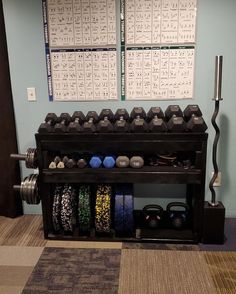 an exercise room with dumbs, weights and wall calendars on the wall behind it