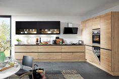 a modern kitchen with wooden cabinets and black counter tops, along with a dining room table