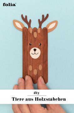 a person holding up a piece of wood with a deer cut out of it's face