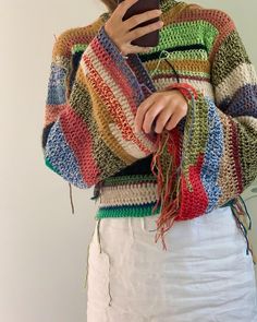 a woman wearing a multicolored sweater and holding a cell phone