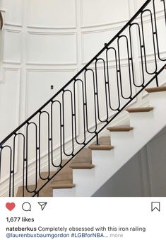 a set of stairs with black railings and wood handrails in an empty room