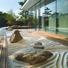 rocks and sand in front of a glass walled building with trees on the other side