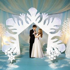 a bride and groom standing in front of a snowflake backdrop