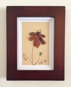 a brown frame holds a paper cut flower in it's center and is hanging on the wall