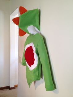 a green frog costume hanging on the wall next to a white door in a room