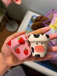 a person holding two small toy animals in their hands with strawberries on the top