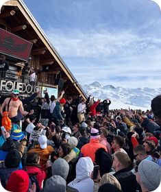 a crowd of people standing around each other in front of a building with a stage