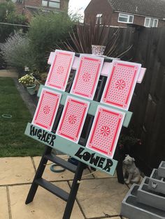 an easel with pink and red cards on it sitting in front of a house