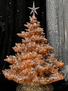 a small christmas tree is sitting in front of a black background with sheer curtains and sequins