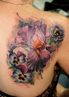 a woman's back with flowers painted on her shoulder and the upper half of her body