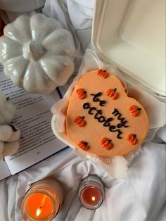 a cake that is sitting on top of a table next to some candles and an open book