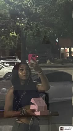 a woman taking a selfie with her cell phone in front of a store window