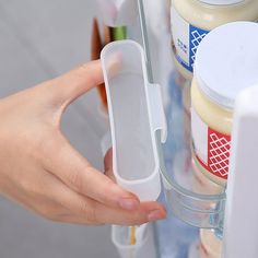 a person holding an object in front of a refrigerator door with food on the shelves