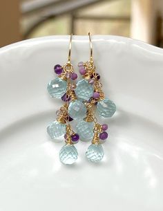 These beauties feature exquisitely faceted Delicate Blue Hydro Quartz (not natural) with clusters of AAA Micro Faceted Amethyst, Phosphosiderite, and Pink Amethyst. Everything has been meticulously hand wrapped with 14k Gold Filled wire. Earring wires are hand forged by me, as always! These are just gorgeous and so full of sparkly goodness!  Length is approximately 2 1/4 inches. 🌿Jewelry arrives beautifully packaged in a sturdy box, wrapped with ribbon or twine. The box is perfect for gift givi Amethyst Earrings Gold, Earrings Fancy, Wire Earring, Fancy Earrings, Pink Amethyst, Quartz Cluster, Amethyst Earrings, Cluster Earrings, Gemstone Colors