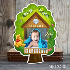 a baby is sitting in front of a tree with a house and winnie the pooh on it