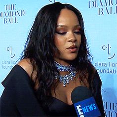 a woman in a black dress is talking to the camera while wearing a choker