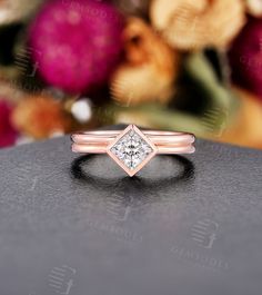 a diamond ring sitting on top of a table next to some pink and yellow flowers