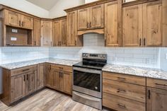 an empty kitchen with wooden cabinets and granite counter tops on the counters, along with a stainless steel dishwasher