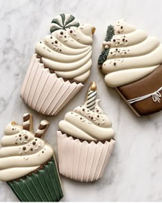 four decorated cupcakes sitting on top of a white counter next to each other