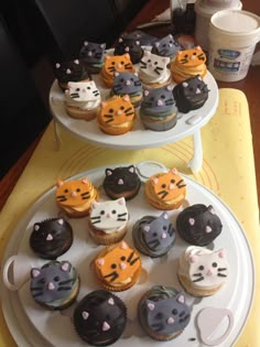 two tiered trays holding cupcakes decorated with cats