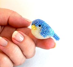 a small beaded bird sitting on top of someone's finger