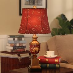 a lamp sitting on top of a wooden table next to a cup and saucer