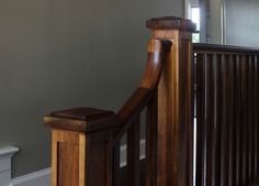 a wooden bannister next to a white toilet in a room with gray walls