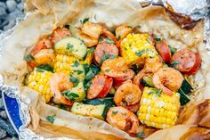 shrimp and corn on the cob in foil wrapper, with garnish