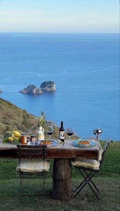 the table is set with food and wine overlooking the water's edge, along with an island in the distance